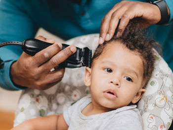 Midsection of man cutting baby boys hair