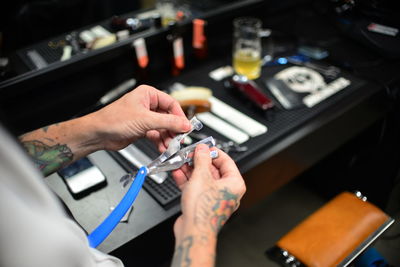 Close-up of tattooed hand of a barber holding straight razor