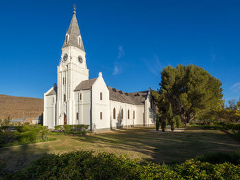 View of white dutch reformed church against blue sky, nieu-bethesda, south africa