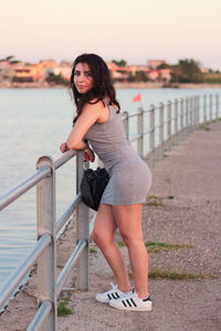 Portrait of smiling woman against railing against sky