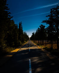 Road amidst trees against blue sky