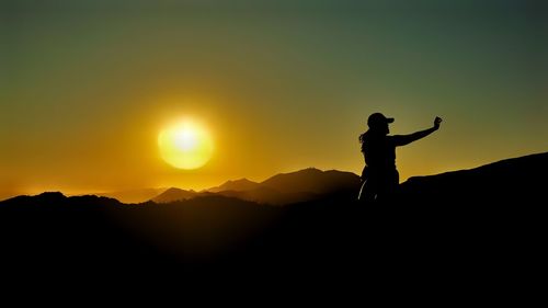 Silhouette man standing on mountain against sky during sunset