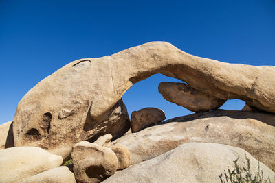 Low angle view of rock formation against clear blue sky