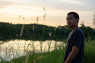 Young man standing on land against sky during sunset