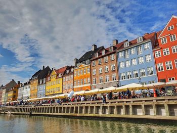 Buildings by river against sky in city