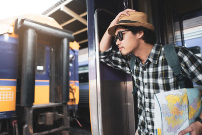 Portrait of tourist wearing sunglasses and hat standing in train