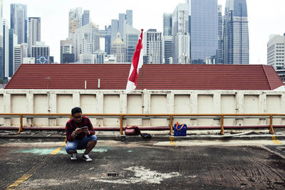 Full length of man sitting against buildings in city