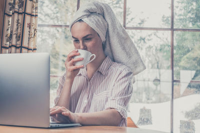 Midsection of man with coffee cup by window
