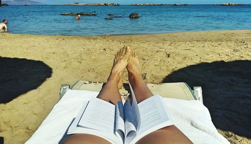 Open book on lap of woman relaxing at beach