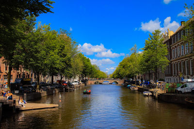 Boats moored in river by city against sky