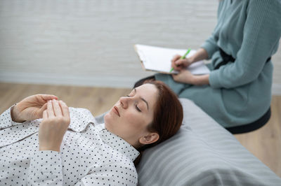 Sad woman lying on psychiatrist's couch at workplace