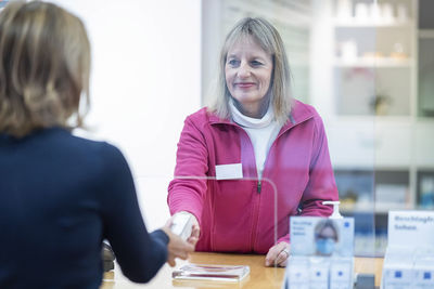 Smiling pharmacist giving medicine to customer