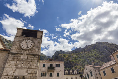 Low angle view of clock tower amidst buildings in city against sky