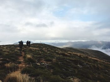 Rear view of people walking on mountain against sky