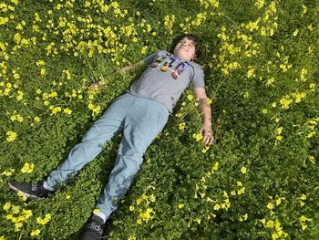 Low section of man standing amidst yellow flowers