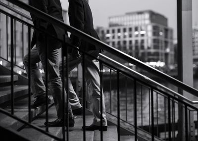 Low section of men standing by railing against buildings in city