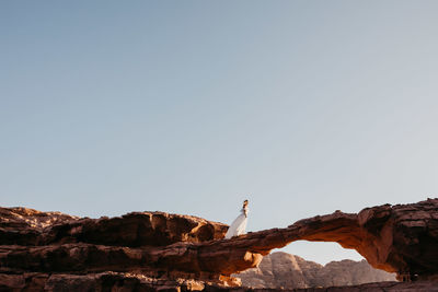 Low angle view of statue on rock formation against clear sky