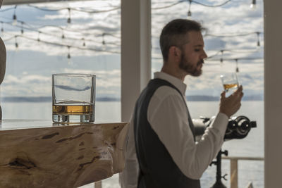 Side view of man having drink indoors