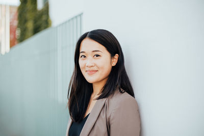 Portrait of smiling businesswoman standing on footpath