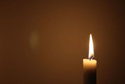 Close-up of lit candle in darkroom