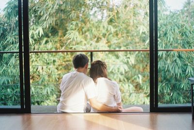 Rear view of couple sitting on window