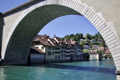 Arch bridge over river against buildings