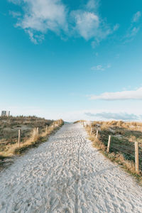 Road amidst field against sky