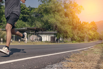 Low section of man walking on road in city