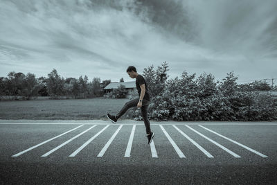 Man jumping on road against sky