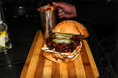 Cropped image of person with burger at restaurant