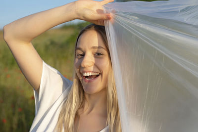 Portrait of young woman standing against sky