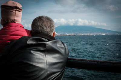 Rear view of man and woman by sea against sky