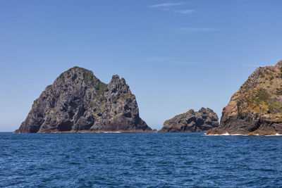 Rock formations in sea against blue sky