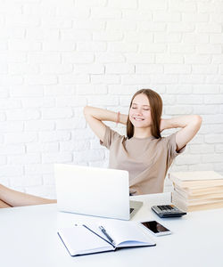 Young woman using mobile phone while sitting on table