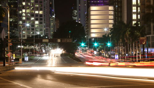 Light trails on road along buildings