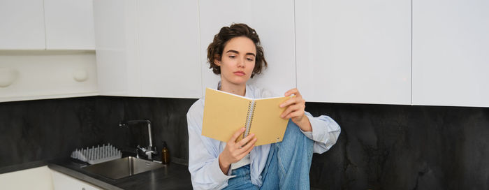 Portrait of young woman standing against wall