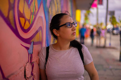 Portrait of young woman wearing sunglasses standing on street