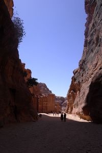 Tourists on rock formation against clear sky