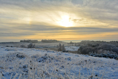 Scenic view of snow covered landscape against sky during sunset