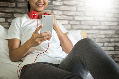 Midsection of smiling woman using mobile phone at home