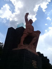 Low angle view of statue against building against sky