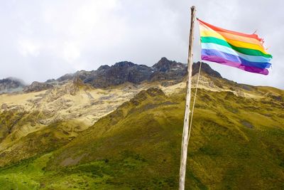 Rainbow flag on mountain against sky