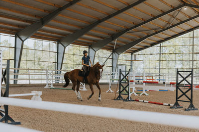 View of female horse rider using indoor riding paddock