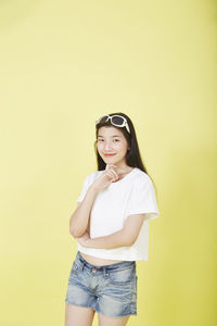 Portrait of smiling woman standing against yellow background