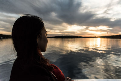 Rear view of woman standing by lake against sky