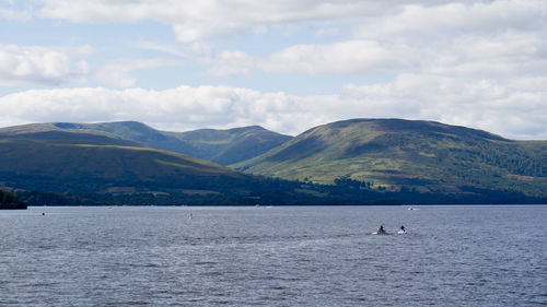 Scenic view of sea by mountains against sky