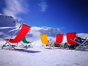 Umbrellas on snow covered field against blue sky