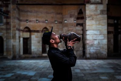 Man drinking from container while standing on walkway