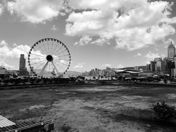 Ferris wheel in city against cloudy sky