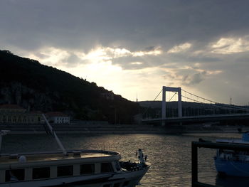 Suspension bridge over sea against sky during sunset